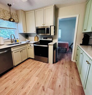 Une cuisine avec un plancher en bois, un four encastré, un four à micro-ondes et un évier.