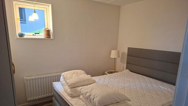 A bedroom with a bed, a bedside lamp, a window with a view, and a radiator. - 5 Star Holiday Home in Uddevalla (Uddevalla)