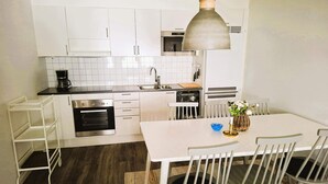 A modern kitchen with white cabinets, a stainless steel oven, a coffee maker, and a dining area with a table and chairs. - 5 Star Holiday Home in Uddevalla (Uddevalla)