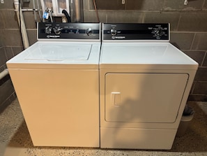 A front-loading white washer and dryer unit with control panels, set against a tiled wall. - Private Pool Retreat, Fire Pit, Game Room (Oak Grove)