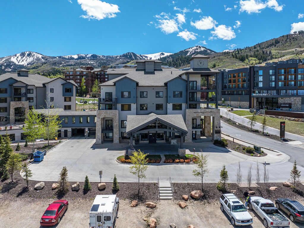 A hotel with multiple buildings, a parking lot, and a mountainous backdrop.
