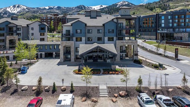 A hotel with multiple buildings, a parking lot, and a mountainous backdrop. - New Listing Canyons Resort, Silverado, Pool, Golf! (Park City)