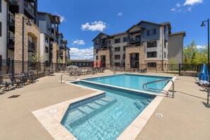 A swimming pool with lounge chairs and umbrellas, surrounded by multi-story buildings with balconies. - New Listing Canyons Resort, Silverado, Pool, Golf! (Park City)
