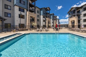 A swimming pool with lounge chairs and umbrellas, surrounded by multi-story buildings with balconies. - New Listing Canyons Resort, Silverado, Pool, Golf! (Park City)