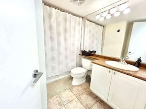 Un bagno con il water, un lavandino e una tenda per la doccia.
