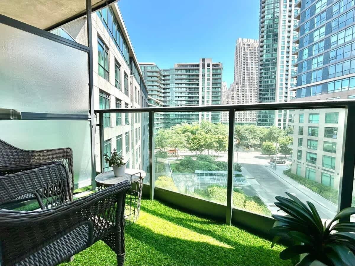 A balcony with a wicker chair, a small table, and a potted plant.