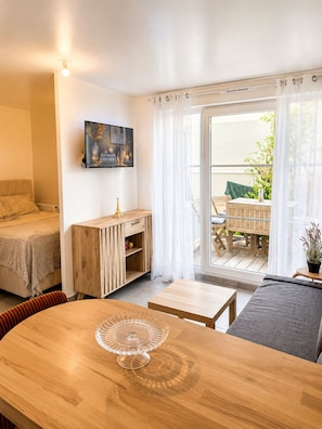 Ein Zimmer mit einem Bett, einem Holzschrank, einem Esstisch mit einer Glasvitrine und einem Balkon mit Tisch und Stühlen.