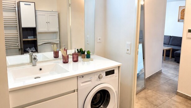 Un baño moderno con lavadora integrada, un espejo grande y un vestidor.