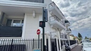 Un edificio residencial de varios pisos con balcones, un acceso mediante portón y una motocicleta estacionada.