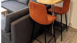 Una sala de estar moderna con un sofá gris, una mesa redonda de madera y dos sillones naranjas.
