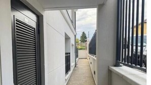 Un pasillo estrecho con una reja metálica a la derecha, una puerta a la izquierda y un ventanal también a la izquierda.