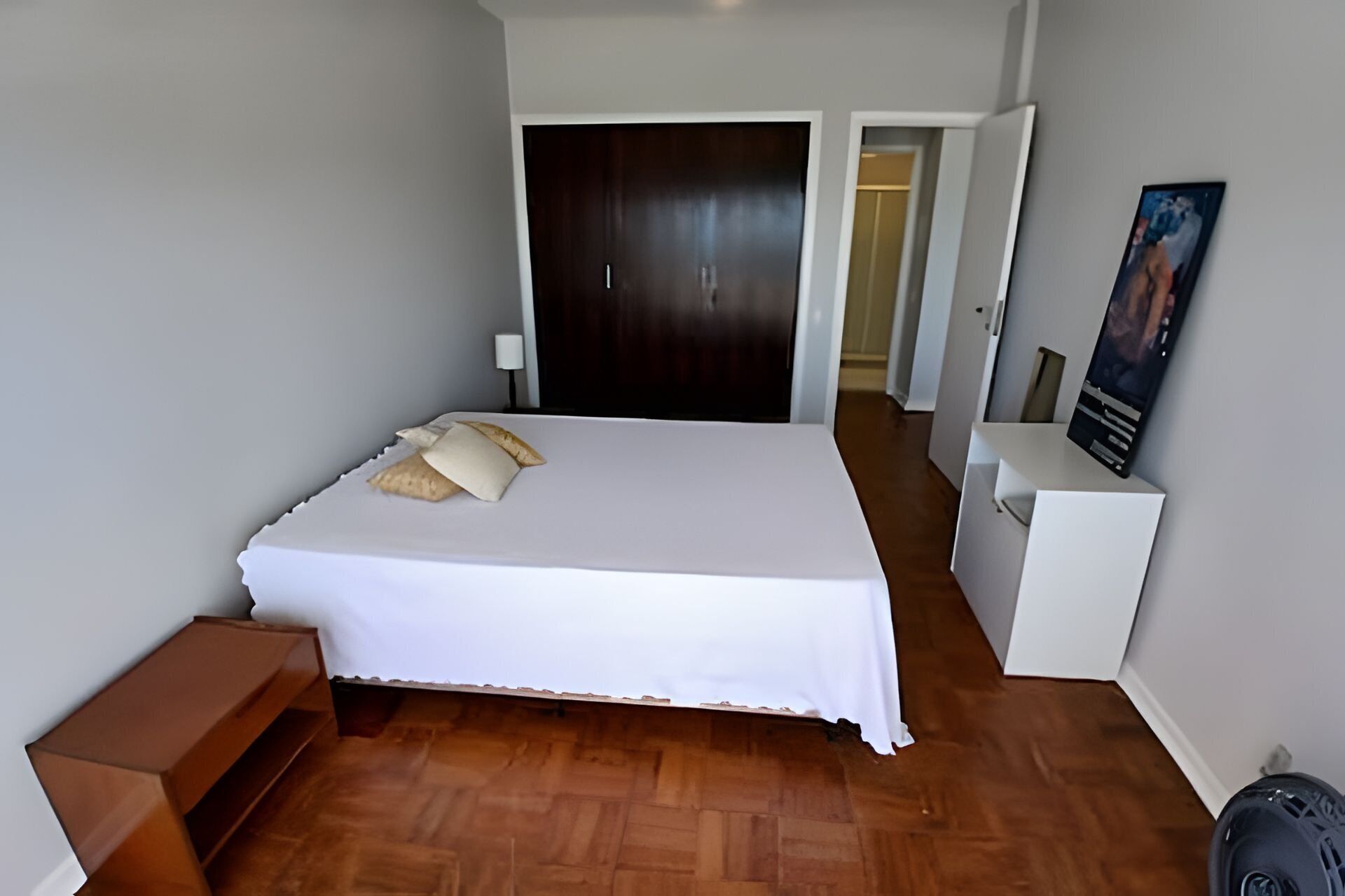 A bedroom with a bed, bedside tables, a wardrobe, and a painting on the wall.
