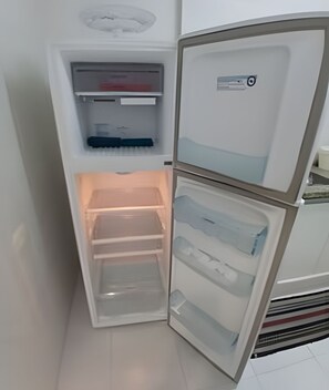 A compact refrigerator with multiple compartments, including a freezer and a main storage area. - SHB Frente ao Mar em Pitangueiras (Guarujá)