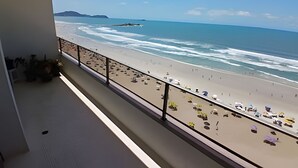 Un balcone con vista sulla spiaggia, un parapetto e alcune piante in vaso.