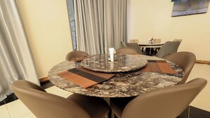 Una mesa de comedor redonda con tapa de mármol, rodeada por cuatro sillas marrones.