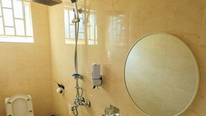 Un baño con inodoro, lavamanos, ducha y espejo.
