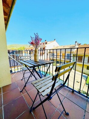 A balcony with a table and chairs, a potted plant, and a view of buildings. - A Cozy Wooden Duplex casa Ski Retreat| 2BR,2BA in a Peaceful Town near Camprodón (Sant Pau de Segúries)