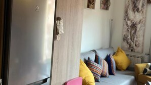 A modern living room with a grey sofa, colorful cushions, a pink chair, and a large painting on the wall. - A Cozy Wooden Duplex casa Ski Retreat| 2BR,2BA in a Peaceful Town near Camprodón (Sant Pau de Segúries)