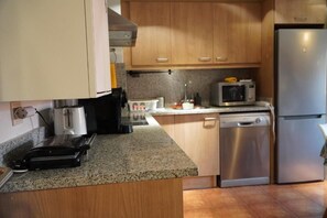 A kitchen with wooden cabinets, a stainless steel refrigerator, a microwave, and a dishwasher. - A Cozy Wooden Duplex casa Ski Retreat| 2BR,2BA in a Peaceful Town near Camprodón (Sant Pau de Segúries)
