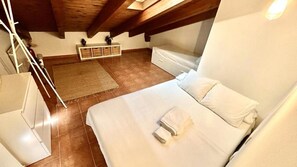 A bedroom with a bed, a small bedside table, a white dresser, and a wooden ceiling beam. - A Cozy Wooden Duplex casa Ski Retreat| 2BR,2BA in a Peaceful Town near Camprodón (Sant Pau de Segúries)