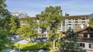 A hotel with a parking lot, trees, and a mountain in the background. - 1 Person Holiday Park Home in Garmisch-partenkirchen (Garmisch-Partenkirchen)