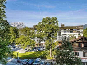Ein Hotel mit Parkplatz, Bäumen und einem Berg im Hintergrund.