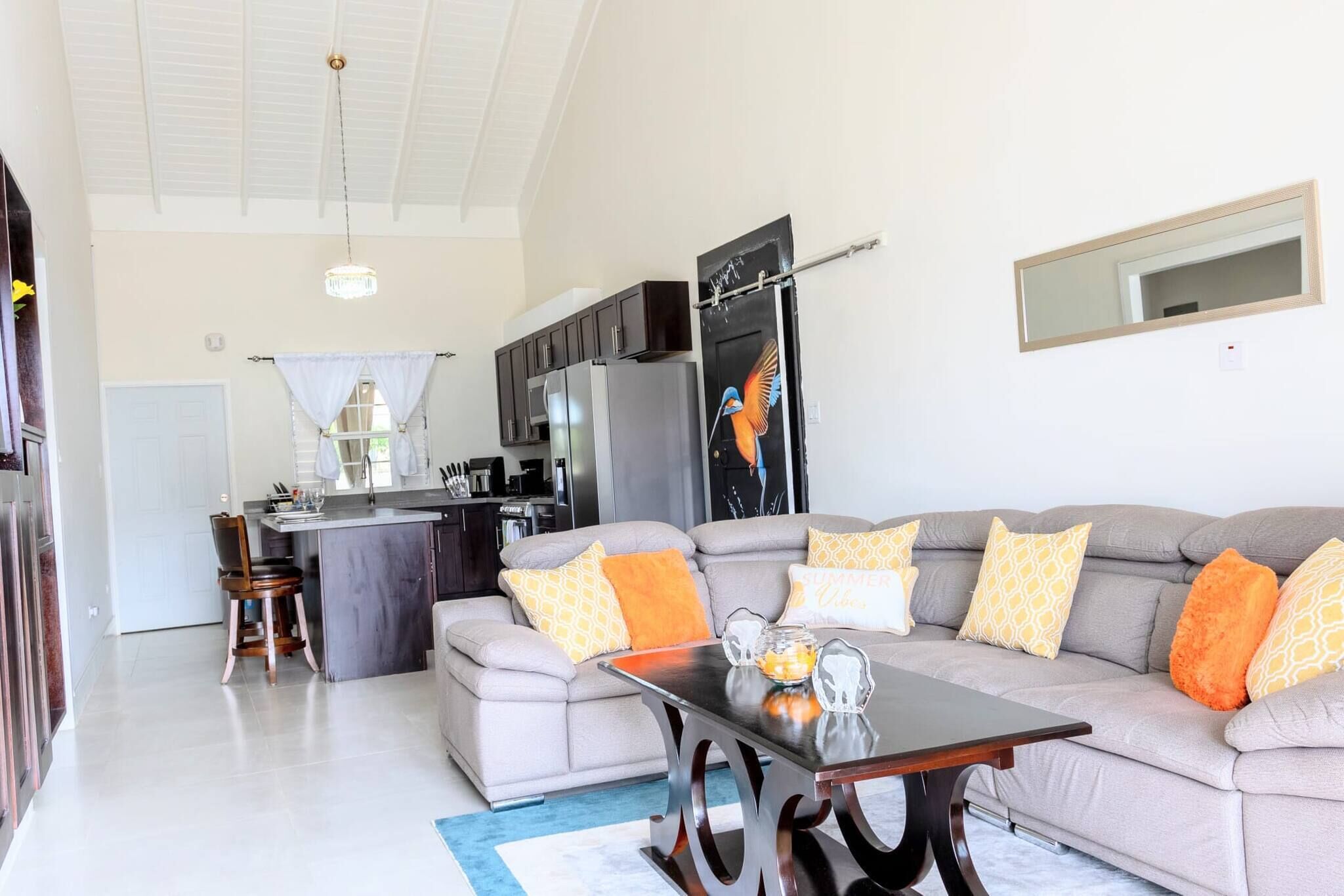 A modern living room with a grey sofa, a coffee table, and a kitchen area in the background.