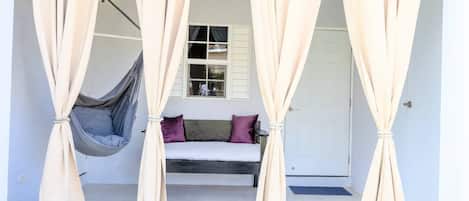 Een kamer met een bed, een hangstoel en beige gordijnen.