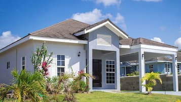 A modern two-story house with a covered porch, a well-maintained lawn, and a clear blue sky.