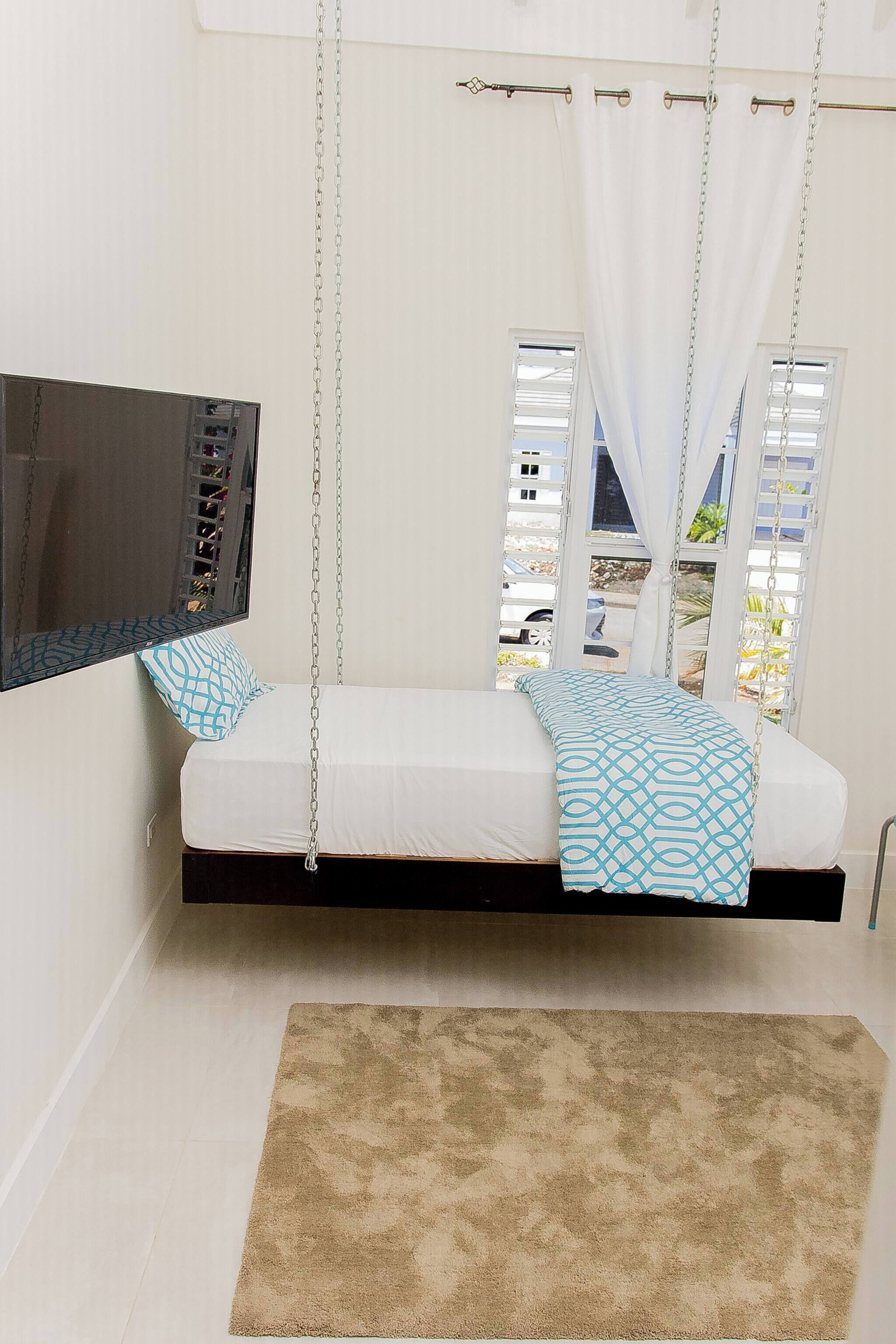 Ein Zimmer mit einer an der Decke befestigten Bettenkonstruktion, einem wandmontierten Flachbildfernseher und einem Blick ins Freie durch ein Fenster.