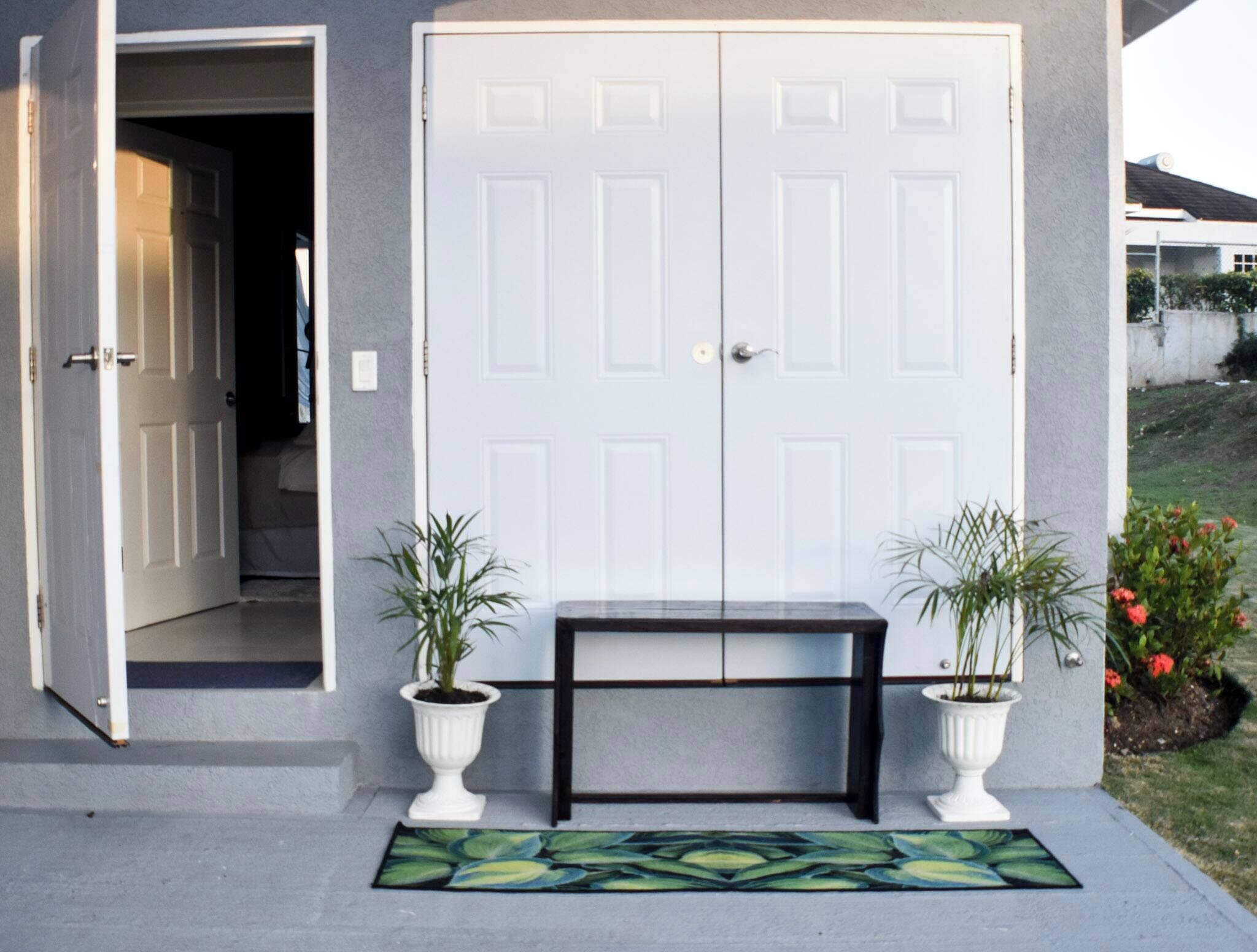 A front door with a bench and two potted plants in front.