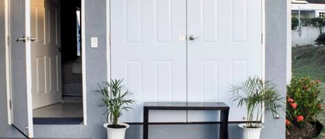 A front door with a bench and two potted plants in front.