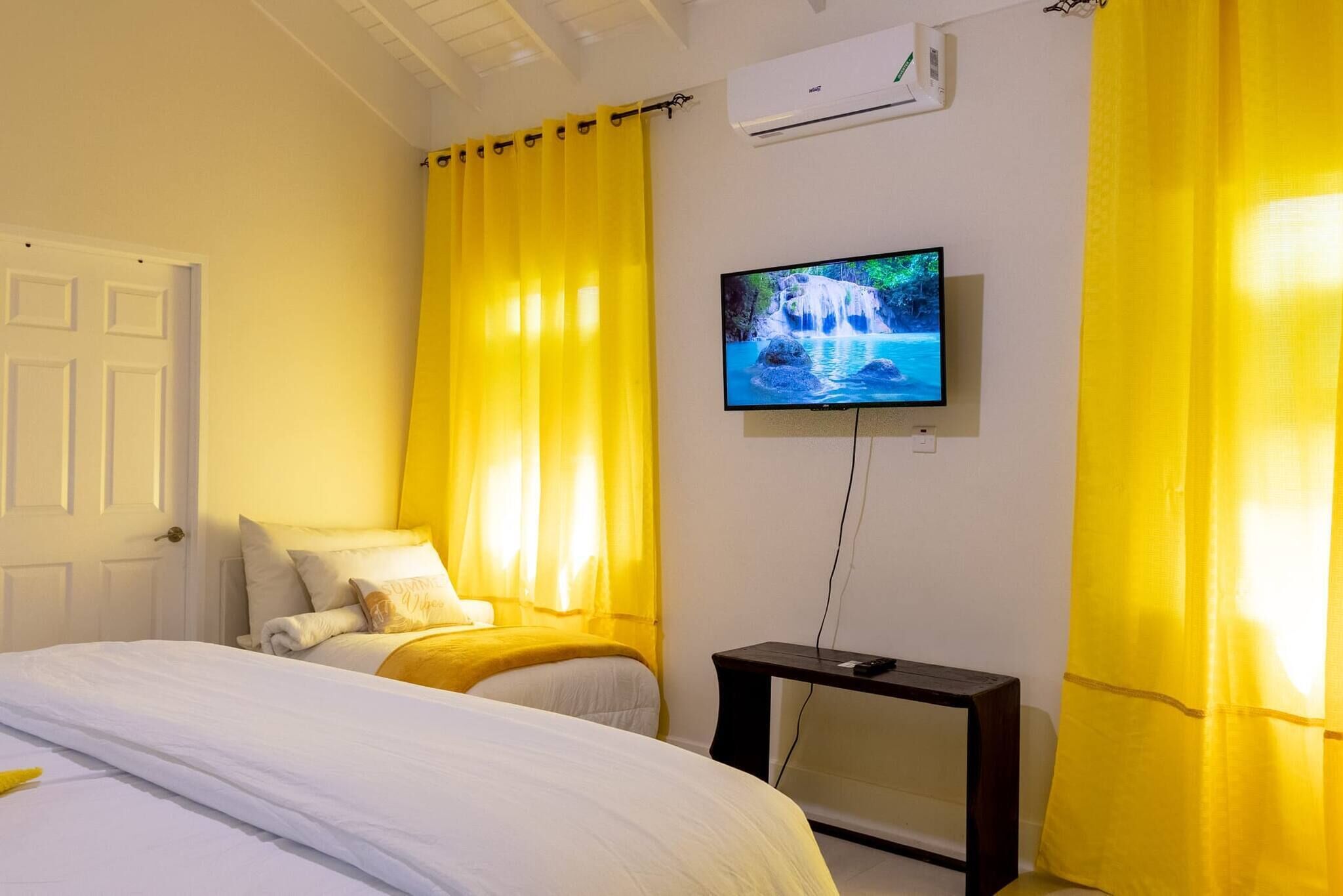A hotel room with a bed, a TV on the wall, and curtains.