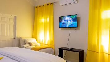 A hotel room with a bed, a TV on the wall, and curtains.