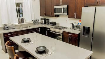 A modern kitchen with a central island, stainless steel appliances, and wooden cabinets.