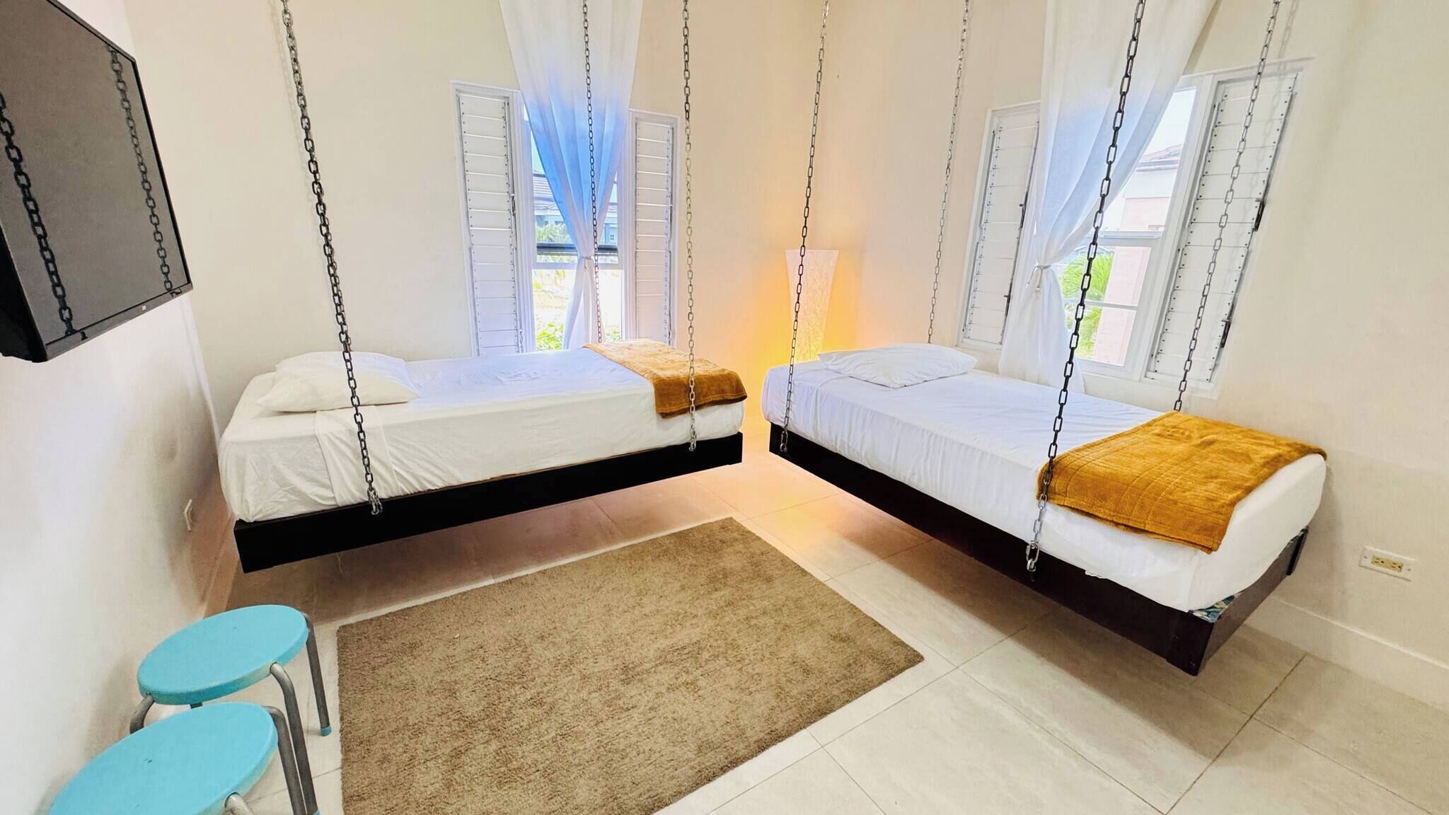A room with two beds suspended from the ceiling, a small table, and a chair.