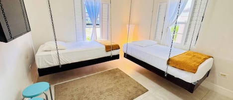 A room with two beds suspended from the ceiling, a small table, and a chair.
