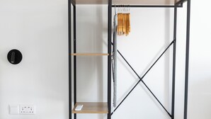 Una stanza con un armadio in legno, una scaffalatura in metallo nero e un tavolino.