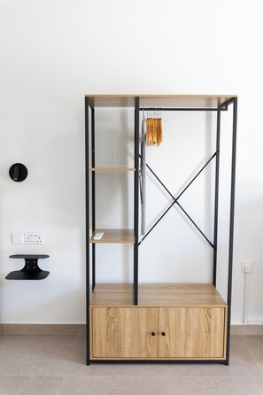 Ein Zimmer mit einem Holzkabinett, einem schwarzen Metallregal und einem kleinen Tisch.