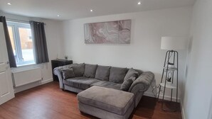 A modern living room with a sectional sofa, a floor lamp, and a radiator.