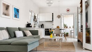 Ein modernes Wohnzimmer mit grauem Sofa, einem Couchtisch und einem Essbereich mit Tisch und Stühlen.