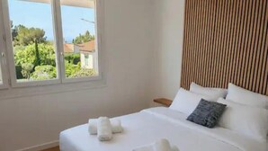 Ein Hotelzimmer mit einem Bett, Kissen und Blick auf Grünfläche.