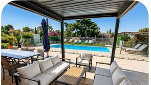 Eine Terrasse im Freien mit Pool, weißen Sitzmöglichkeiten und einem Tisch.