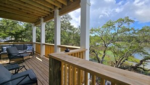 Eine überdachte Terrasse im Freien mit Holzwertkasten, einer Couch und Sesseln.