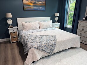A bedroom with a bed, two nightstands, a dresser, a window with curtains, and a painting on the wall. - 4bedroom house in fantastic Gulf Shores with long pier for fishing and gathering (Gulf Shores)