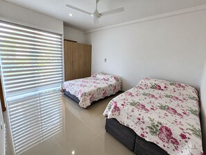 Un dormitorio con dos camas, ventilador de techo y armario.