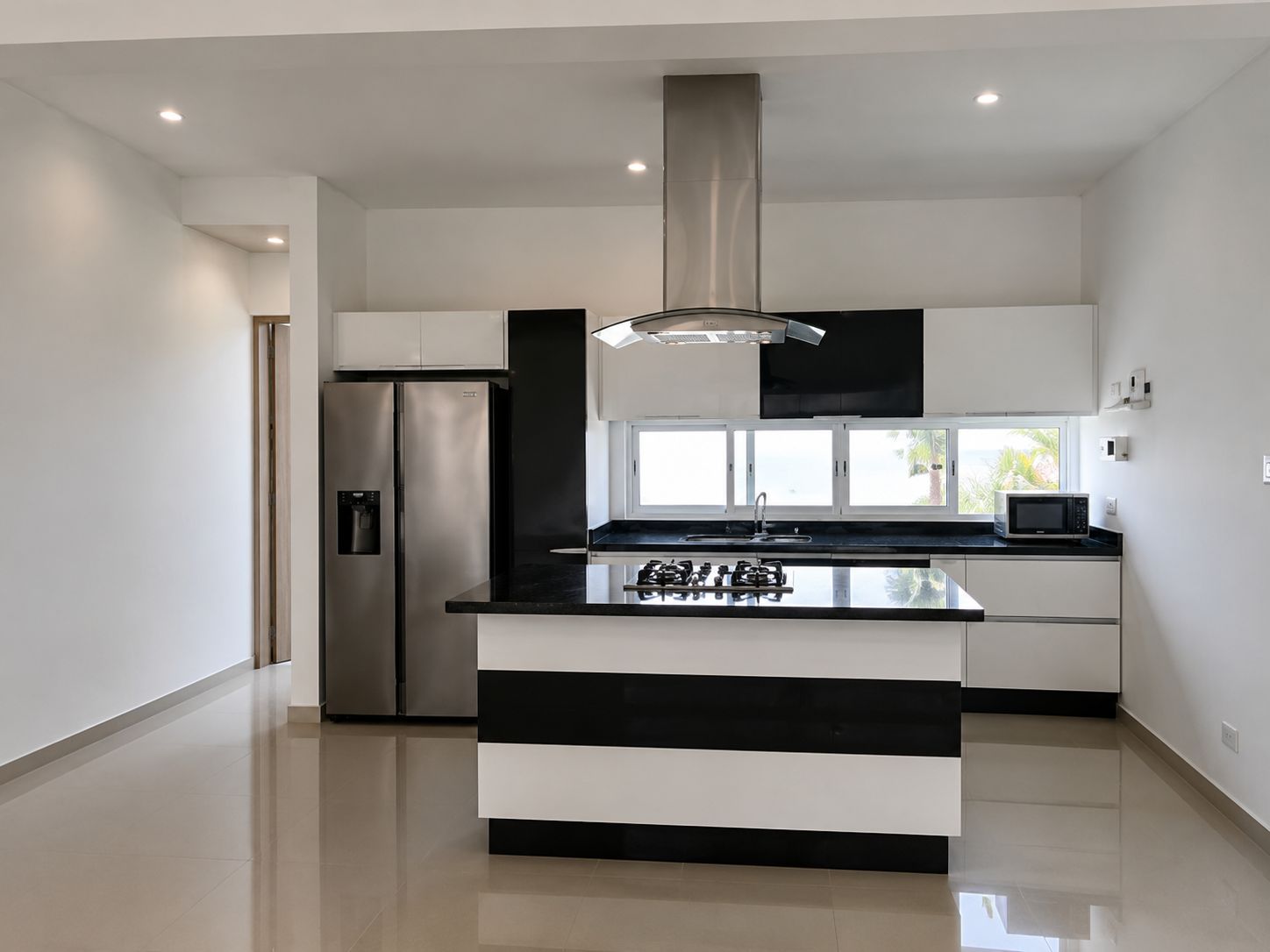 A modern kitchen with a central island, stainless steel appliances, and a window providing natural light.