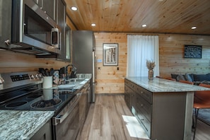 Una cocina moderna con electrodomésticos de acero inoxidable, suelo de madera y encimera de mármol.