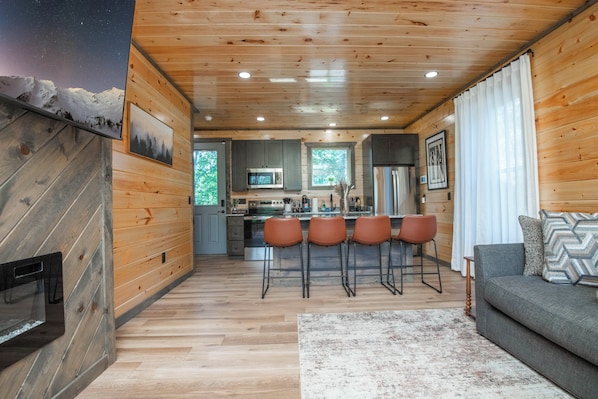 Interior acogedor de una cabaña con cocina, comedor y sala de estar con chimenea.