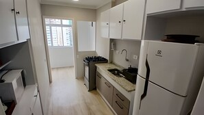 Una cocina moderna con gabinetes blancos, estufa integrada y un lavabo.